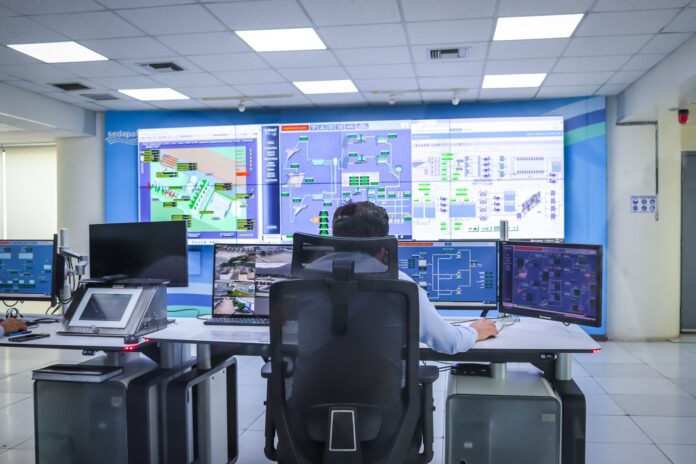Operator w nowoczesnej sterowni nadzoruje systemy przemysłowe Operator w nowoczesnej sterowni nadzoruje systemy przemysłowe