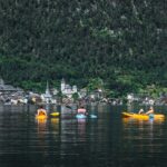Trzech kajakarzy na jeziorze Hallstatt z widokiem malowniczej wioski