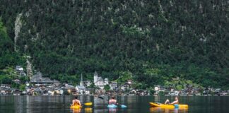 Trzech kajakarzy na jeziorze Hallstatt z widokiem malowniczej wioski