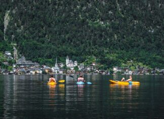 Trzech kajakarzy na jeziorze Hallstatt z widokiem malowniczej wioski