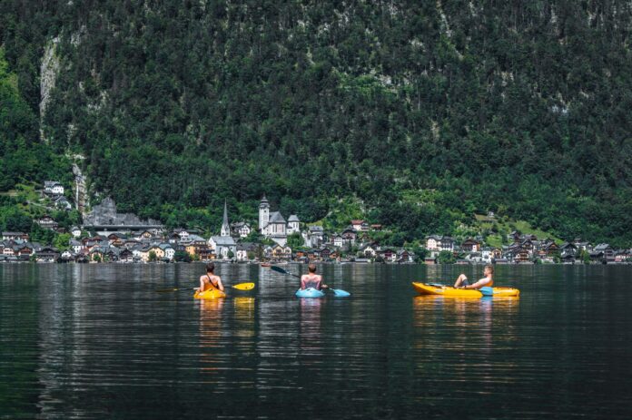 Trzech kajakarzy na jeziorze Hallstatt z widokiem malowniczej wioski Trzech kajakarzy na jeziorze Hallstatt z widokiem malowniczej wioski